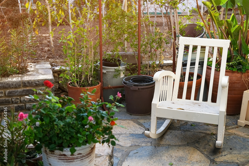 White chair next to potted plants, cute patio with rocking chair, courtyard with flowers White chair next to potted plants, cute patio with rocking chair, courtyard with flowers