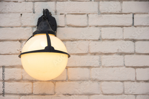 Obraz na plátně A burning round antique lantern on a light brick wall, copy space