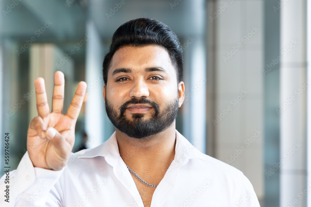 Happy smiling young south asian Indian man pointing up 3 fingers, showing number three, third place or 3 points gesture Happy smiling young south asian Indian man pointing up 3 fingers, showing number three, third place or 3 points gesture