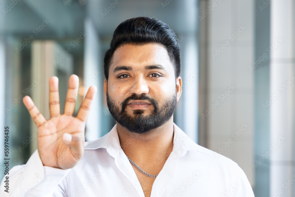 Happy smiling young south asian Indian man pointing up 4 fingers, showing number four, forth place or 4 points gesture Happy smiling young south asian Indian man pointing up 4 fingers, showing number four, forth place or 4 points gesture