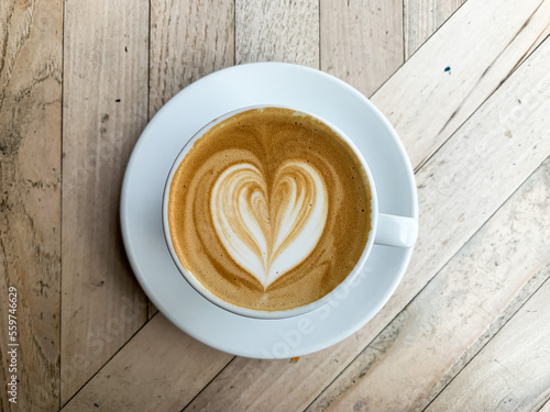 A cup of coffee latte on a wooden table. A mug of flat white coffee, latte, cappuccino on a wooden background. Coffee art. Heart flower shape latte art