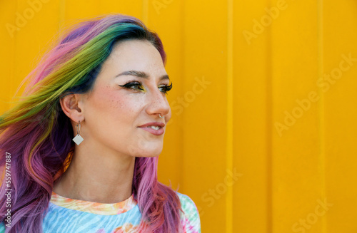 Smiling young woman wearing nose ring in front of yellow wall