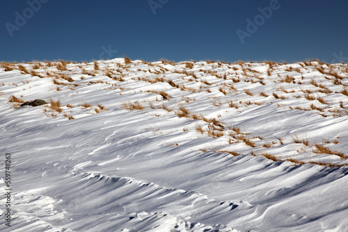 Abstract winter background of frozen snow in the mountains and blue sky photo