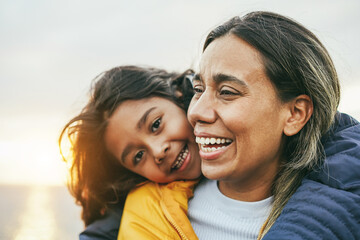 Happy latin mother and daughter having fun during winter time - Mom day and family love concept - Focus on mom face