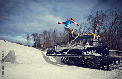 Snowboarder grinding on snowcat blade