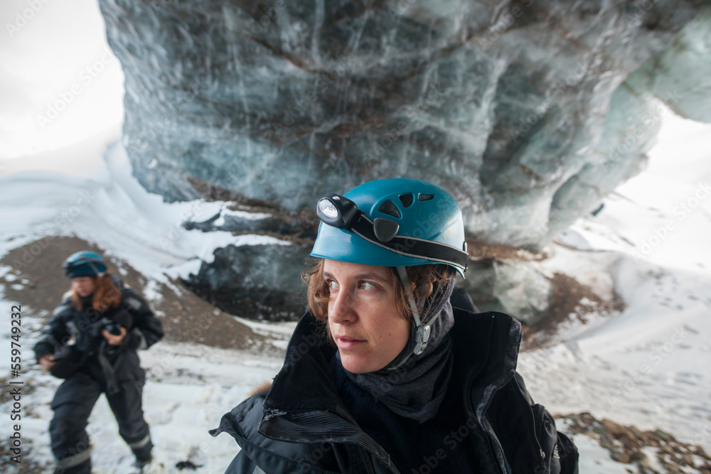 A young woman under a large ice arch on Tellbreen, Svalbard. A young woman under a large ice arch on Tellbreen, Svalbard.