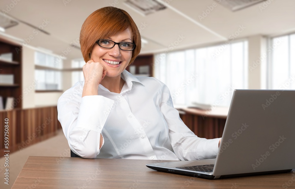 Young woman sitting and working on laptop in modern office. Young woman sitting and working on laptop in modern office.