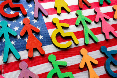 US flag and multi-colored figures with the symbol of a disability person. photo