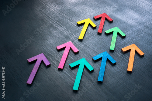 Multi-colored arrows on a dark surface as a symbol of teamwork and unity.