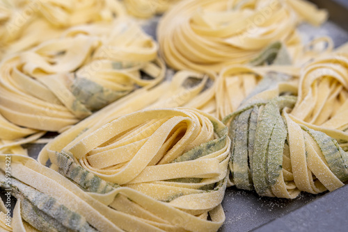 Nidos de pasta fresca  artesanal, fettuccine al basilico - tallarines de albahaca fresca caseros hechos a mano en casa photo