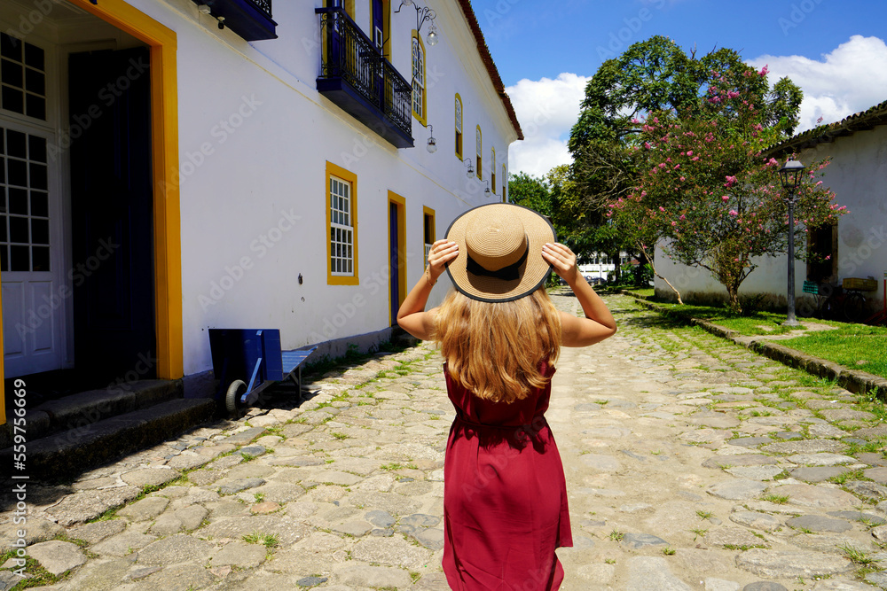 Traveler girl walks through the streets in preserved historic colonial town of Paraty, Brazil