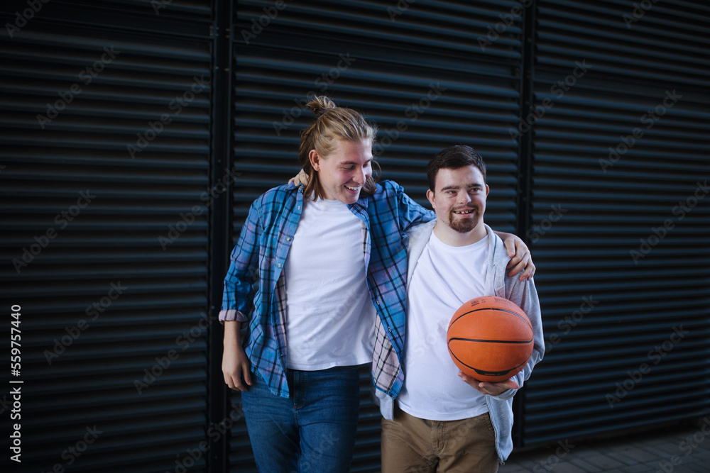 Man with down syndrome playing basketball outdoor with his friend. Concept of friendship and