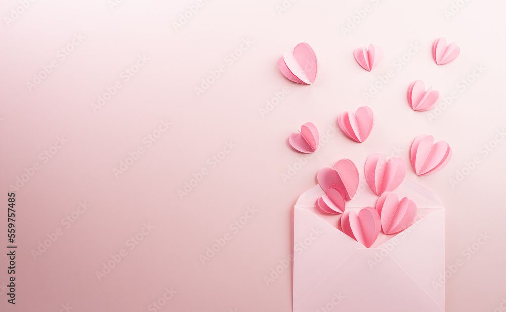 Pink paper hearts splash out on pastel pink paper background. Love and Valentine's day concept.