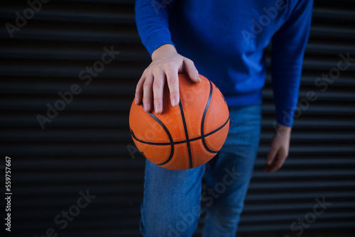 Close-up of young man holding basketball ball,outdoor in city. Youth culture.