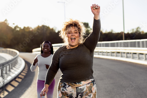 Fototapeta Naklejka Na Ścianę i Meble -  Two excited young plus size women jogging together.