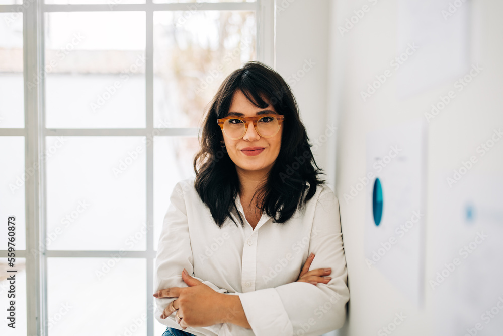 Business woman looking at the camera as she stands in an office Business woman looking at the camera as she stands in an office