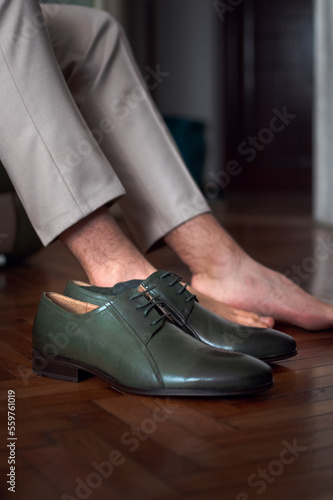 Shot of a groom putting on green leather shoes.