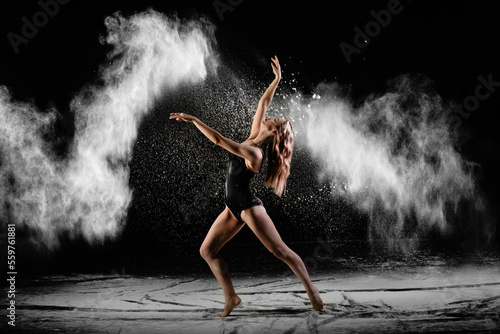 Young beautiful woman with spread flour on the air on a black background © meatbull
