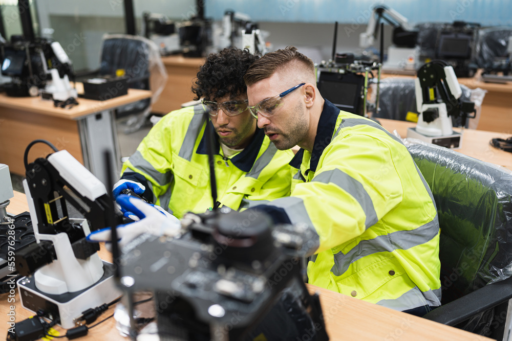 Two caucasian engineer man learning control and repair arm robot in class Two caucasian engineer man learning control and repair arm robot in class