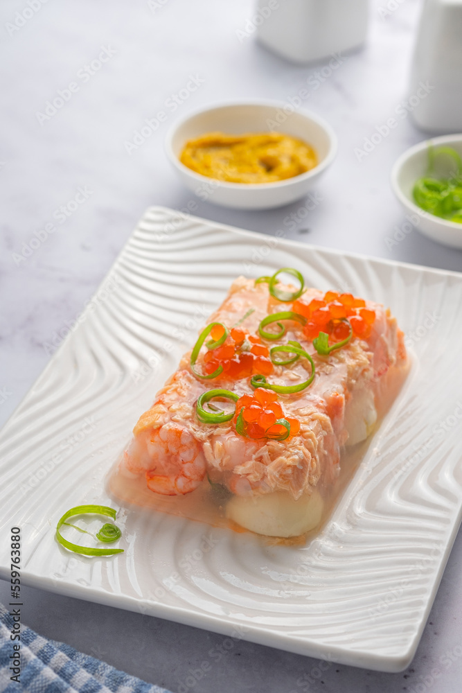 Fish aspic of shrimp, salmon and boiled quail eggs garnished with red caviar and green onions on a white plate on a light background. Recipes fish and seafood. Fish aspic of shrimp, salmon and boiled quail eggs garnished with red caviar and green onions on a white plate on a light background. Recipes fish and seafood.