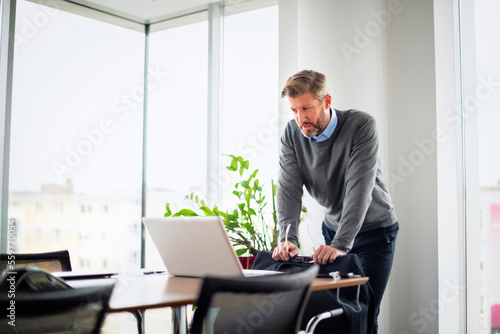 Tired businessman using laptop and working at the office