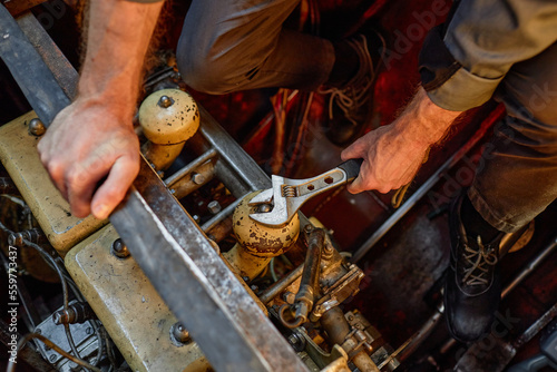 Close up of unrecognizable worker repairing engine and unscrewing bolts with metal wrench, copy space photo