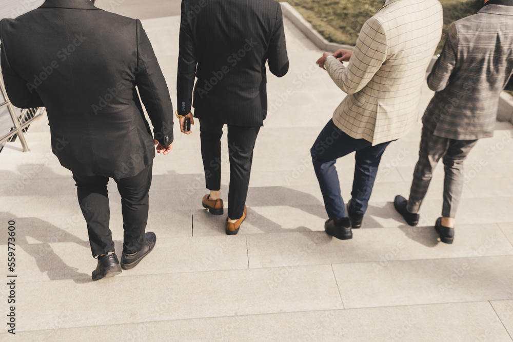 A group of business men in suits descends the city stairs. outdoors. Working break. Collaboration and Teamwork A group of business men in suits descends the city stairs. outdoors. Working break. Collaboration and Teamwork