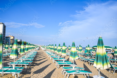 Deckchairs and parasols on sandy beach near the sea. Exotic beach in summer. Vacation, travel and tourism concept. 