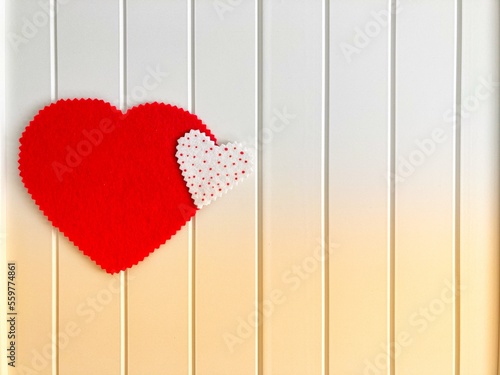 Two handmade red felt hearts on white retro wooden table. Valentine's day background. 
