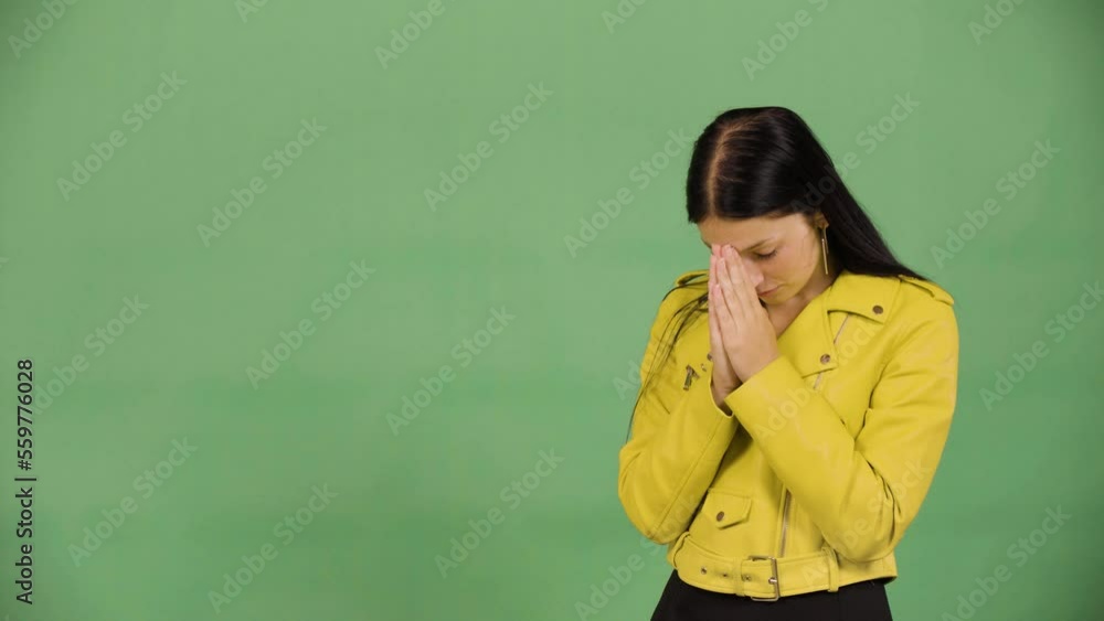 A young beautiful Caucasian woman prays with her hands clasped together - green screen studio A young beautiful Caucasian woman prays with her hands clasped together - green screen studio