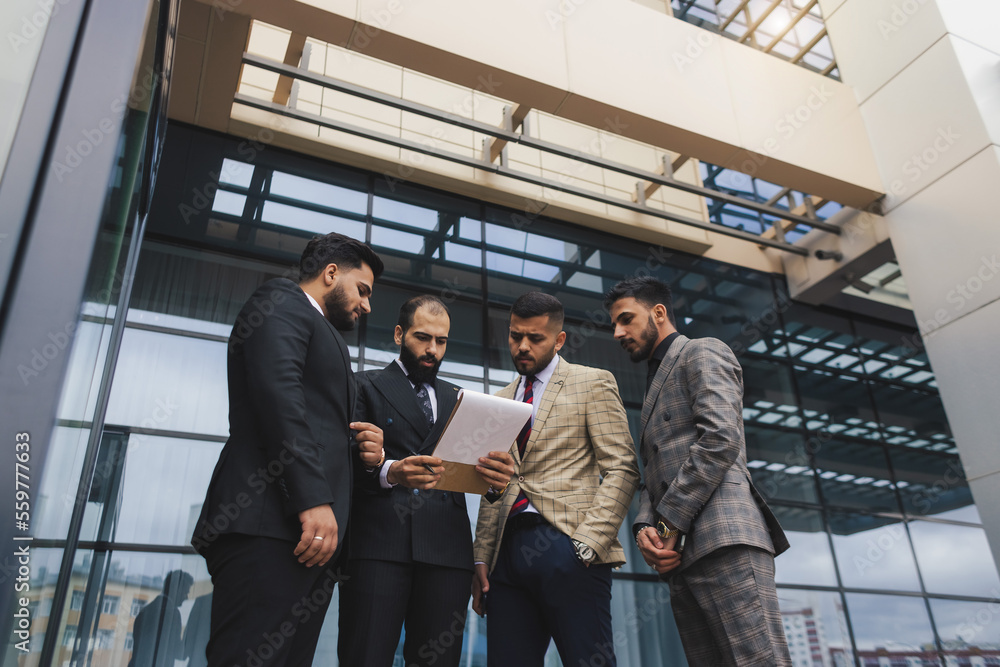 Business people outdoor meeting. Men in jackets discuss working moments together by brainstorming. Teamwork and partnership in business processes Business people outdoor meeting. Men in jackets discuss working moments together by brainstorming. Teamwork and partnership in business processes