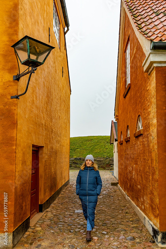 Helsingor, Denmark A Danish woman walks by an old orange and ochre-colored house. © Alexander