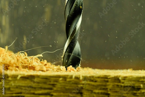Macro image of the drill bit. Rotating drill bit and flying wood chips. Concept for woodworkers, craftsmen, DIYers. Macro and close-up image photo