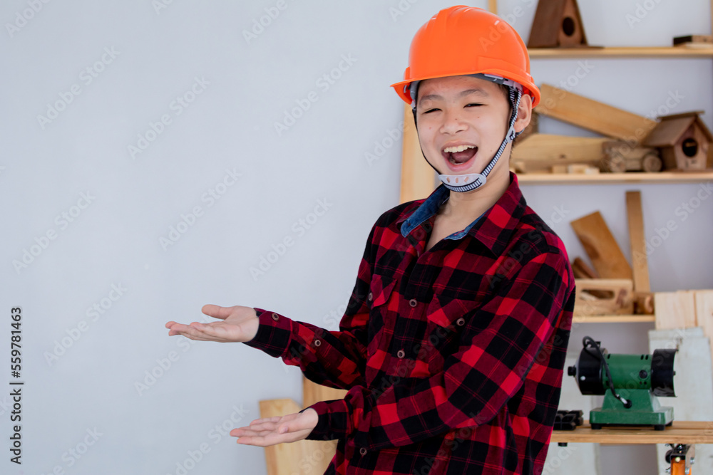 Lovely Asian carpenter boy acting present his work in front of DIY woodworking table carpentry shop with copy space Lovely Asian carpenter boy acting present his work in front of DIY woodworking table carpentry shop with copy space