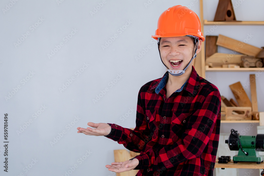 Lovely Asian carpenter boy acting present his work in front of DIY woodworking table carpentry shop with copy space Lovely Asian carpenter boy acting present his work in front of DIY woodworking table carpentry shop with copy space