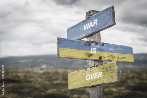 war is over text on wooden signpost with the ukranian flag painted on it. Peace and war concept.