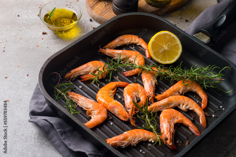 Shrimps on stone background. Grilled prawns with rosemary and lemon. 