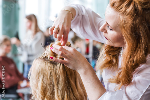 Competition stylists hairdressers at the exhibition of hairstyles and makeup. Hairdresser creates hairstyle for his model.