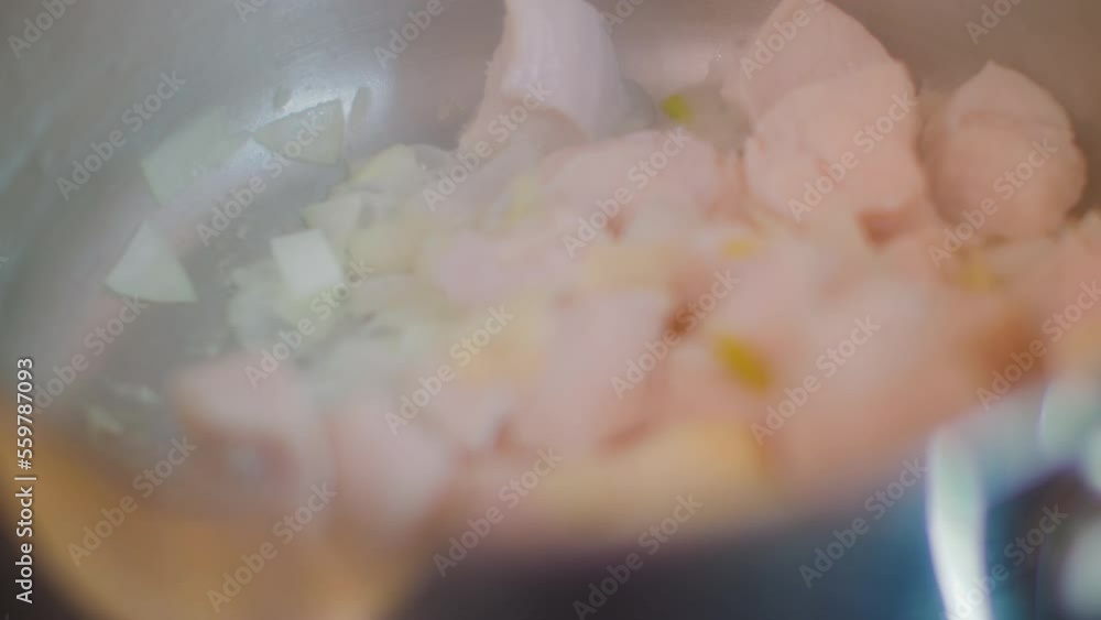 Pieces of chicken meat and onion are stewed in metal saucepan. First stage of cooking Asian Tom Yam soup. Pieces of chicken meat and onion are stewed in metal saucepan. First stage of cooking Asian Tom Yam soup.
