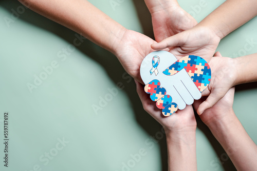 Father, Mother, Children holding heart jigsaw puzzle, Color puzzle symbol of awareness for autism spectrum disorder family support. Autism World Awareness Day.