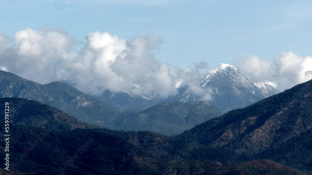 White clouds glide between the mountain peaks. Time laps of mountain peaks and clouds. Mountain delightful landscape White clouds glide between the mountain peaks. Time laps of mountain peaks and clouds. Mountain delightful landscape