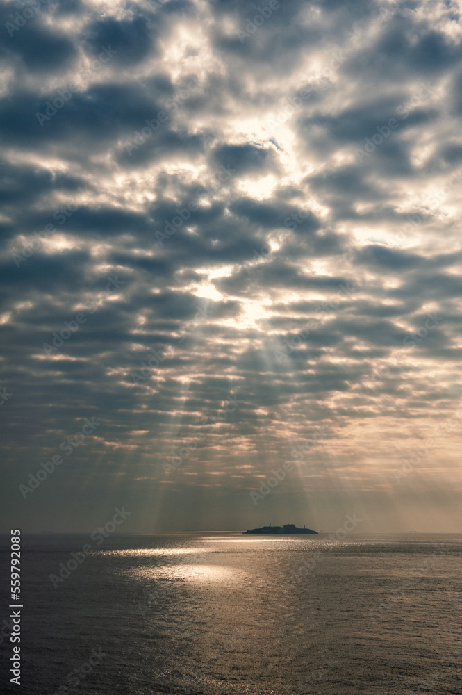 Beautiful landscape with Sun beams breaks through clouds over sea water