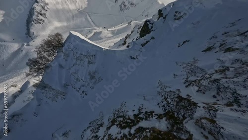 Snow mountain summit speed low dive couloir to ski resort slope ropeway picturesque panorama nature aerial dynamic view. FPV sport drone shot skiing extreme leisure activity landscape. Slo-mo 50fps 4k