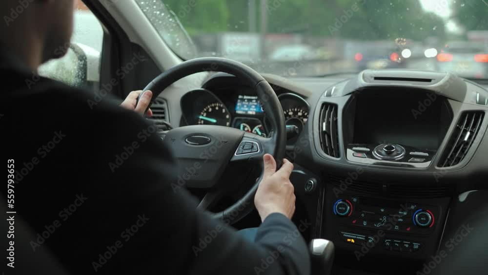 Man drives a car along the road in the city during the rain. Man drives a car along the road in the city during the rain.