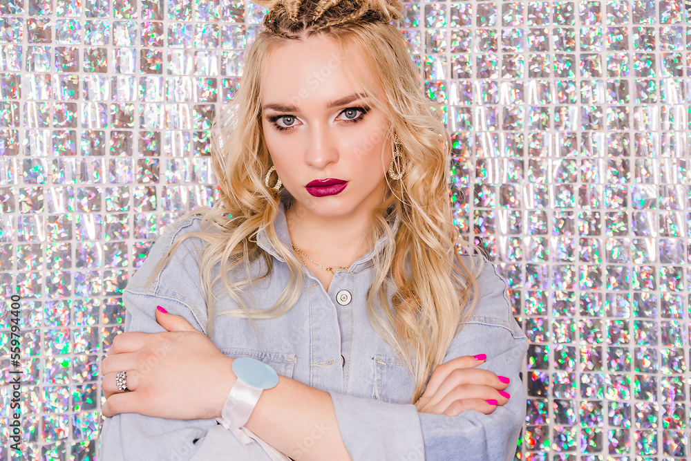Blonde girl, with bright make-up and hairstyle in denim overalls posing on a glitter background Blonde girl, with bright make-up and hairstyle in denim overalls posing on a glitter background