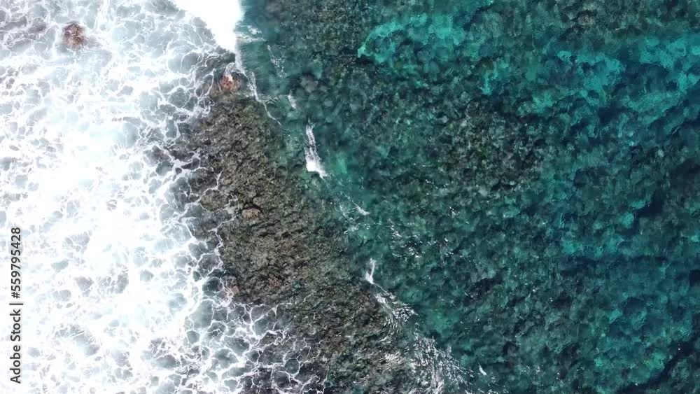 Océan indien filmé par drone sur l'île de la Réunion. Coraux et eau bleu turquoise transparente avec vague et houle sur le sable de la plage.