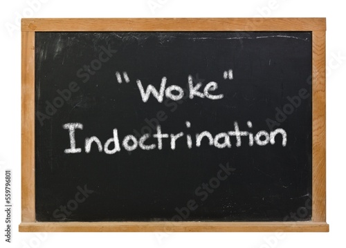 Фотография Woke indoctrination written in white chalk on a black chalkboard isolated on whi