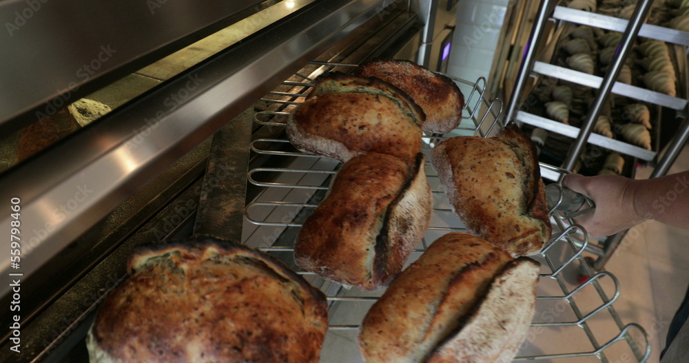Baker pulling breads from oven and putting on shelves stacked2 Baker pulling breads from oven and putting on shelves stacked2