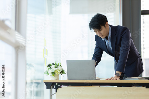 Portrait of a handsome businessman working on his laptop at his desk in the office.
