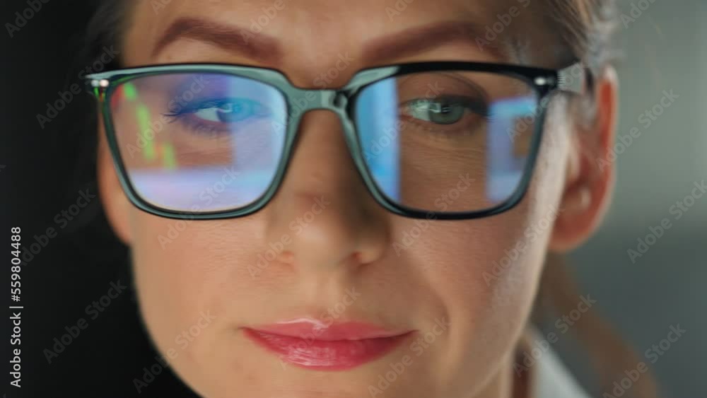 Woman in glasses looking on the monitor and working with charts at night Woman in glasses looking on the monitor and working with charts at night